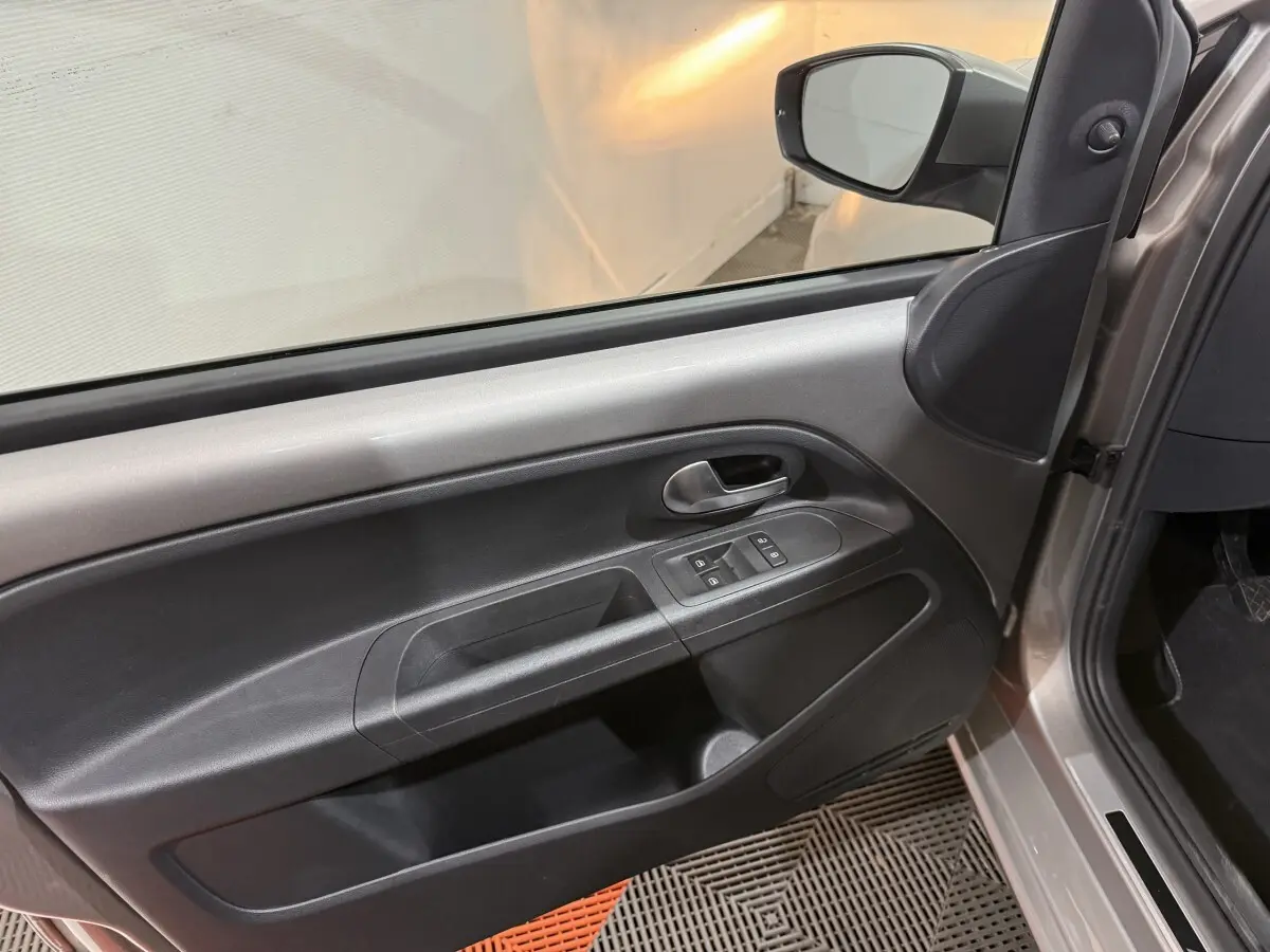 Intérieur de la porte avant gauche gris foncé du Volkswagen UP 2022 avec commandes de vitres et poignée métallique.