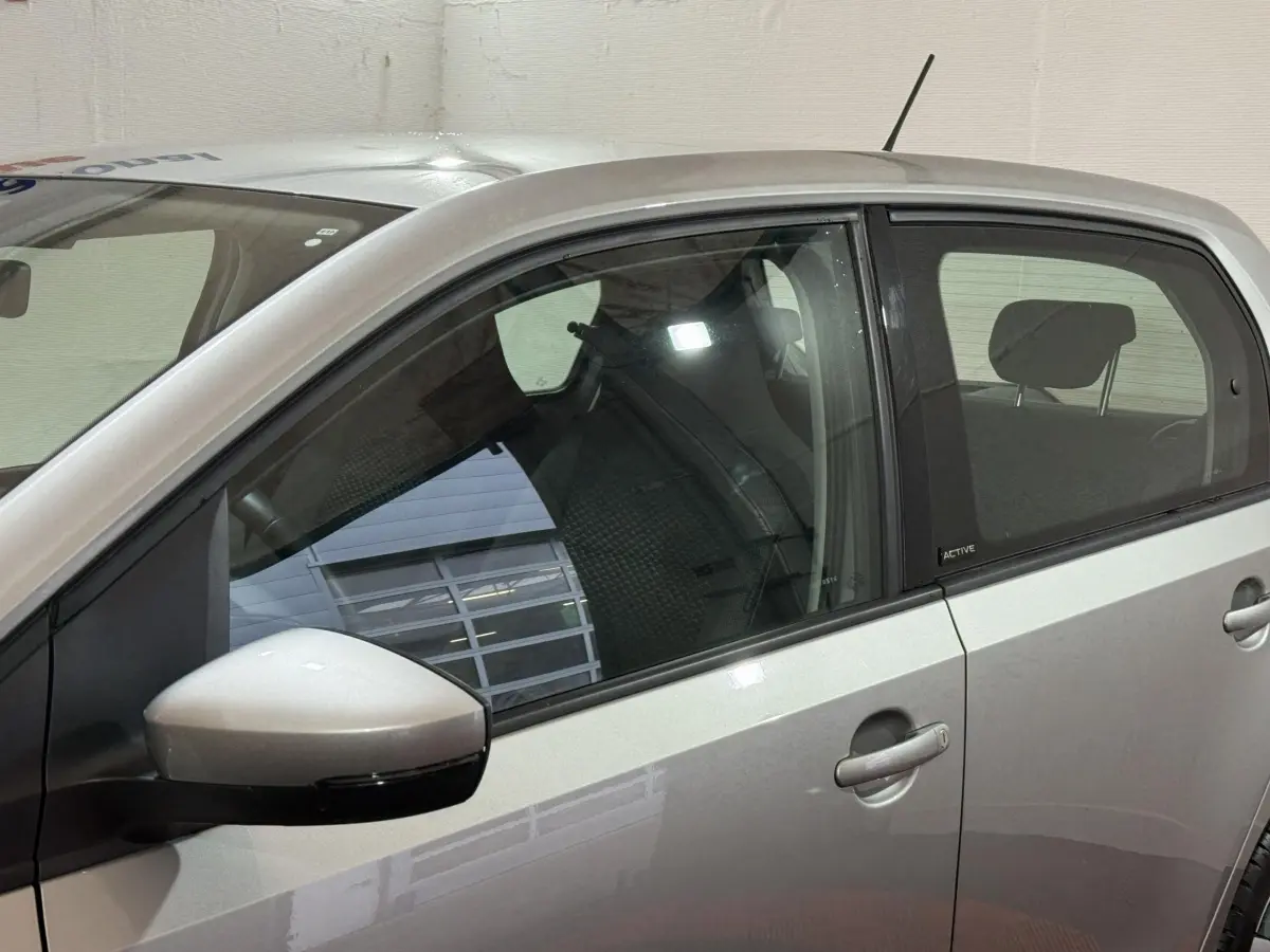Vue latérale côté gauche d'une Volkswagen Up grise foncée avec badge Active sur la porte arrière.