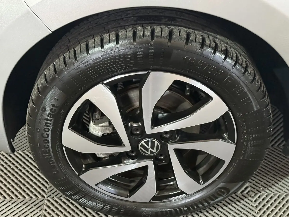 Gros plan sur la roue avant droite d'une Volkswagen Up gris foncé avec jante alliage bicolore et logo VW central.