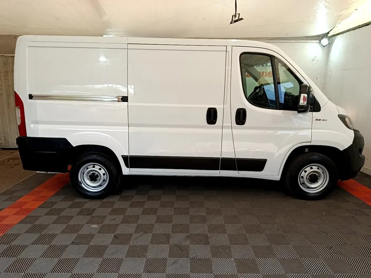 Profil droit du FIAT Ducato Fourgon blanc 2021 avec bandeaux noirs et jantes acier simples.