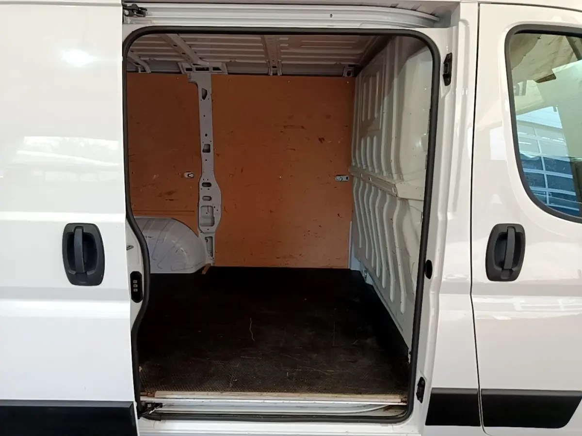 Vue latérale droite du fourgon blanc FIAT Ducato 2.3 Multijet 120 avec porte coulissante ouverte sur l’espace de chargement vide.