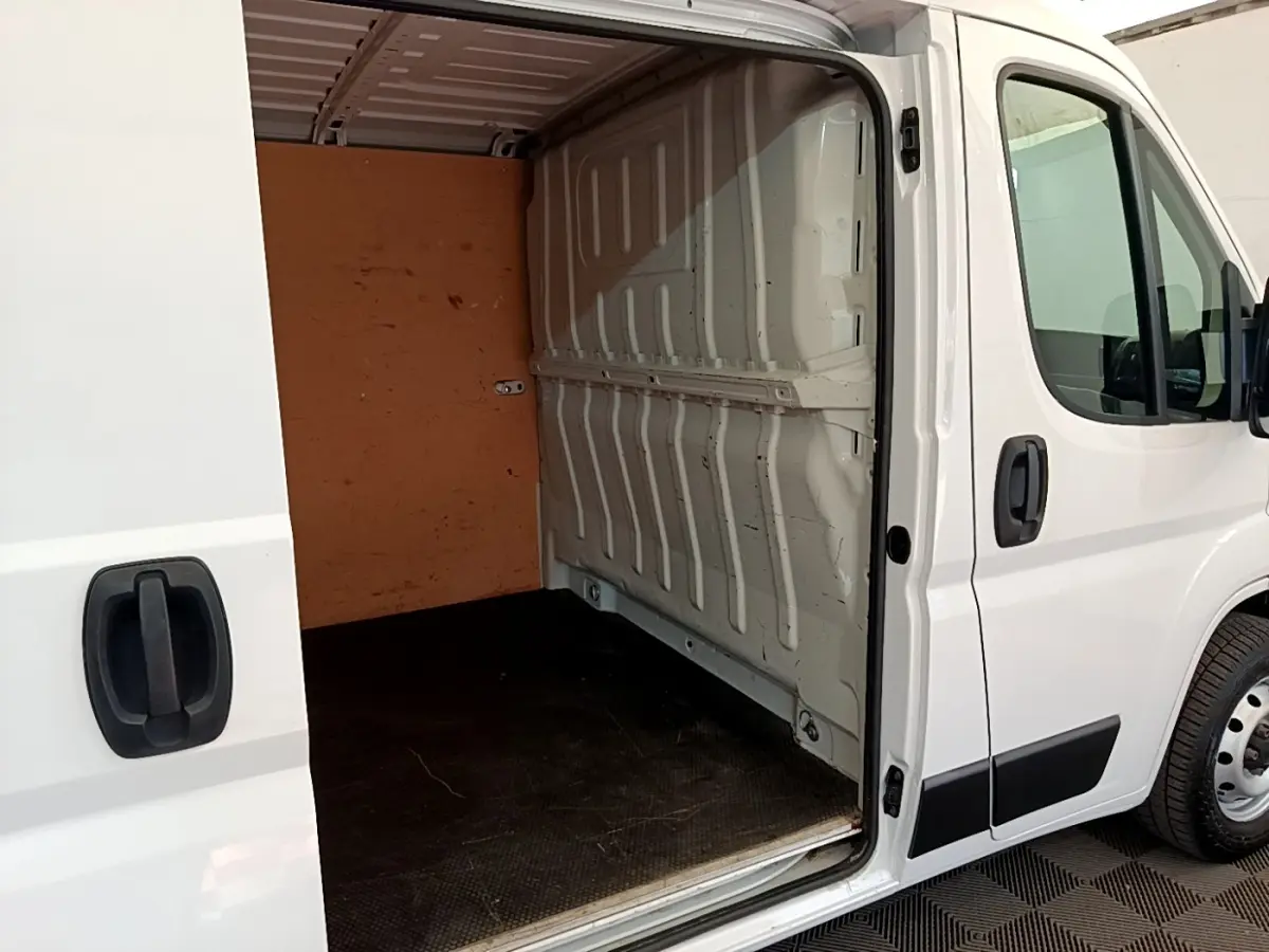 Vue latérale droite d’un fourgon blanc FIAT Ducato 2.3 Multijet 120 avec porte coulissante ouverte montrant l’espace de chargement vide.