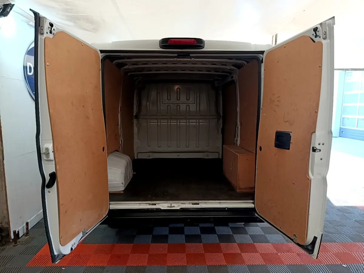 Vue arrière du FIAT Ducato Fourgon blanc 2021 avec portes ouvertes montrant l’espace de chargement vide et habillage bois intérieur.