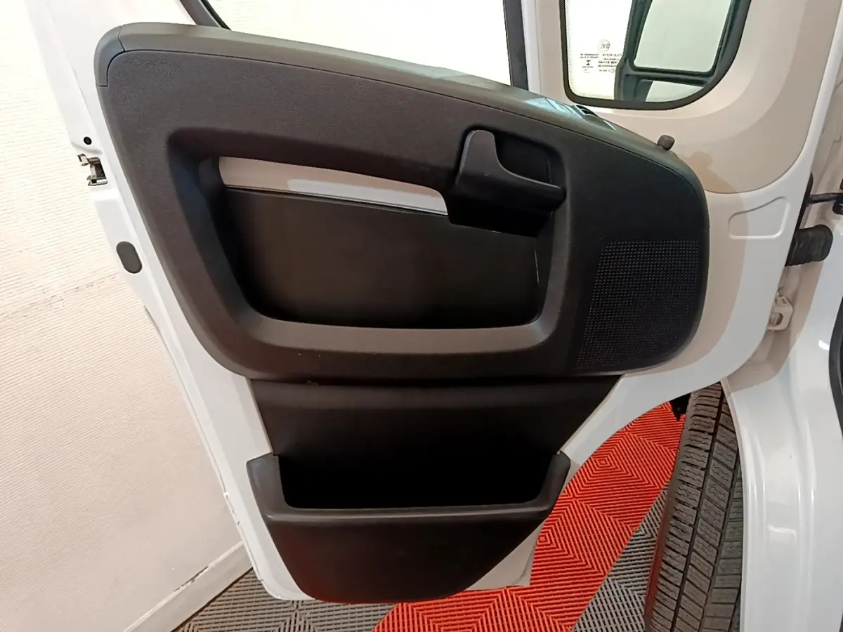 Vue rapprochée de la porte avant droite blanche du Fiat Ducato Fourgon 2021, avec panneau intérieur noir et poignée intégrée.