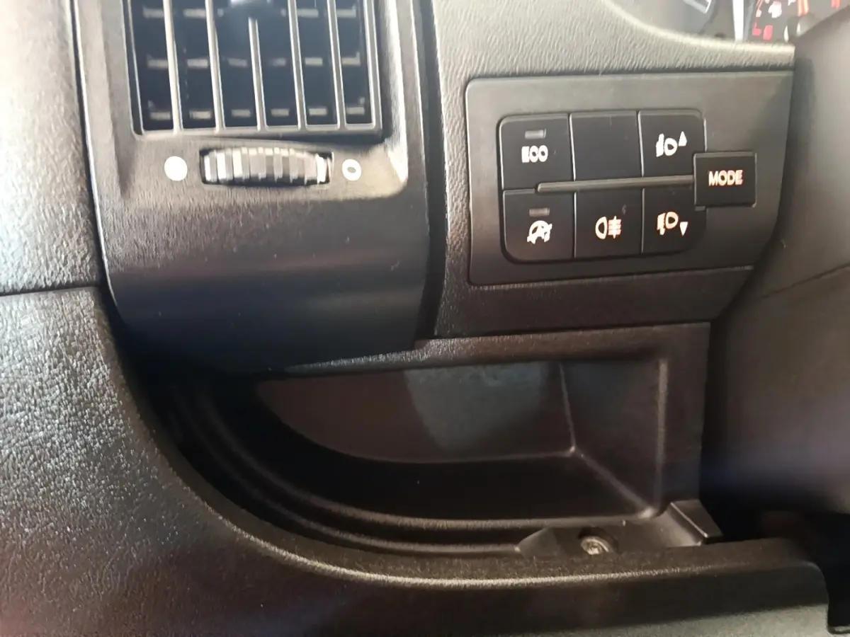 Gros plan sur les commandes d'éclairage et la ventilation côté conducteur du tableau de bord noir du Fiat Ducato Fourgon blanc.