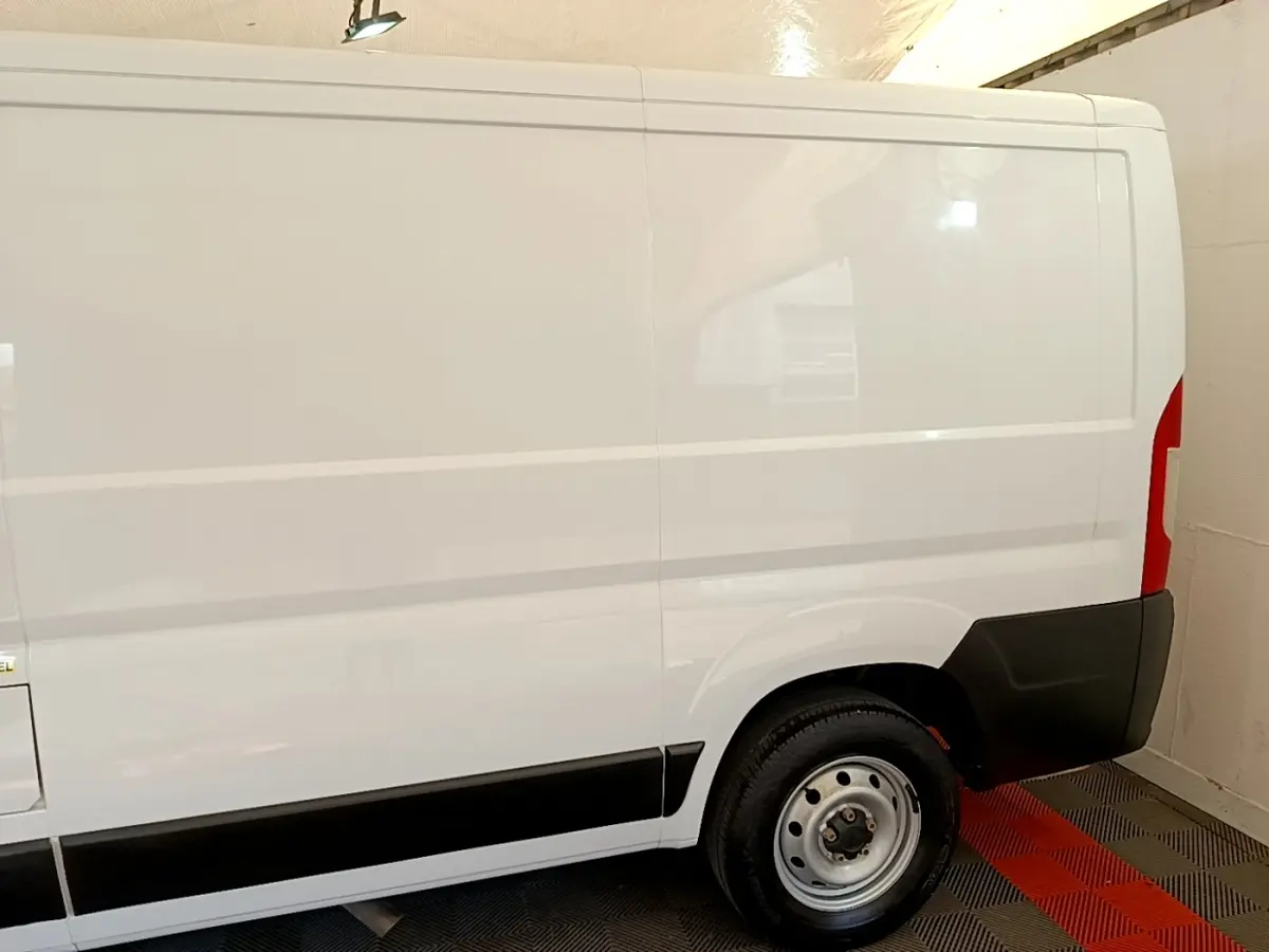 Vue latérale droite d’un fourgon FIAT Ducato blanc 2021 avec jante acier et protections noires sur bas de caisse.