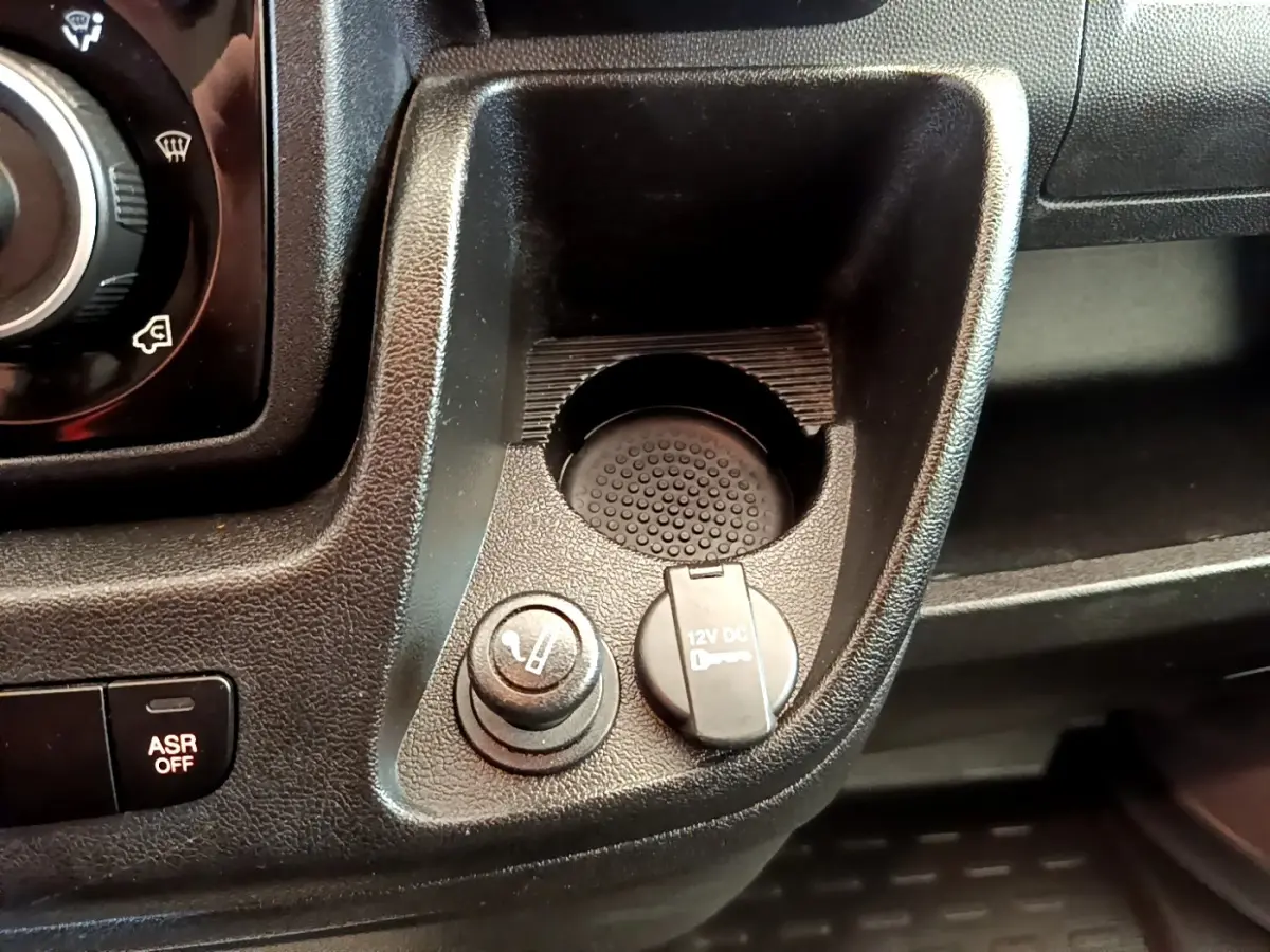 Détail de la console centrale noire du Fiat Ducato Fourgon 2021 avec prise 12V et allume-cigare vue de dessus.