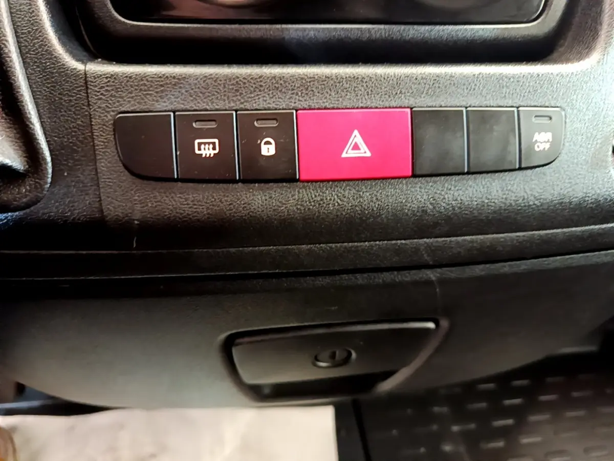 Gros plan sur les boutons de commande noirs et rouge du tableau de bord du Fiat Ducato Fourgon blanc, version 2021.