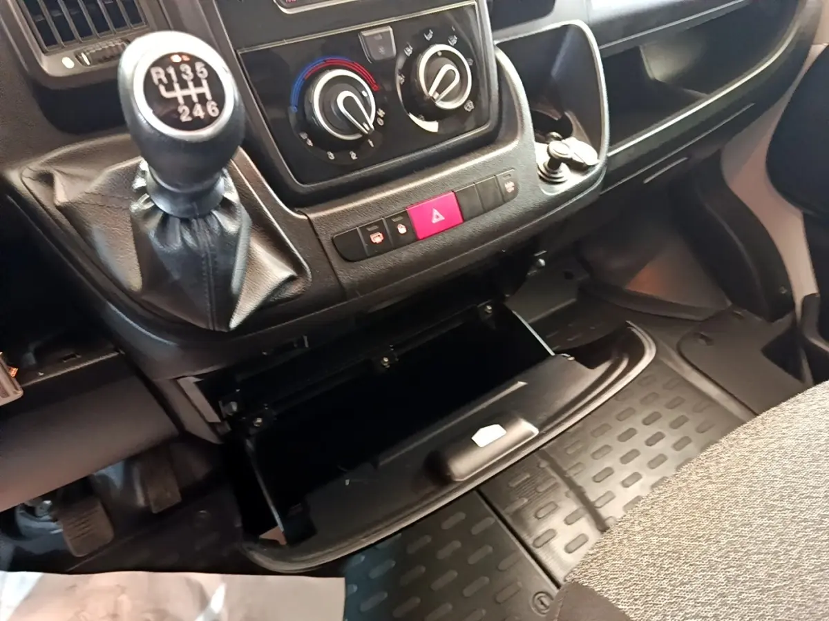 Gros plan intérieur sur la console centrale et le levier de vitesse manuel du Fiat Ducato Fourgon, avec boîte ouverte.