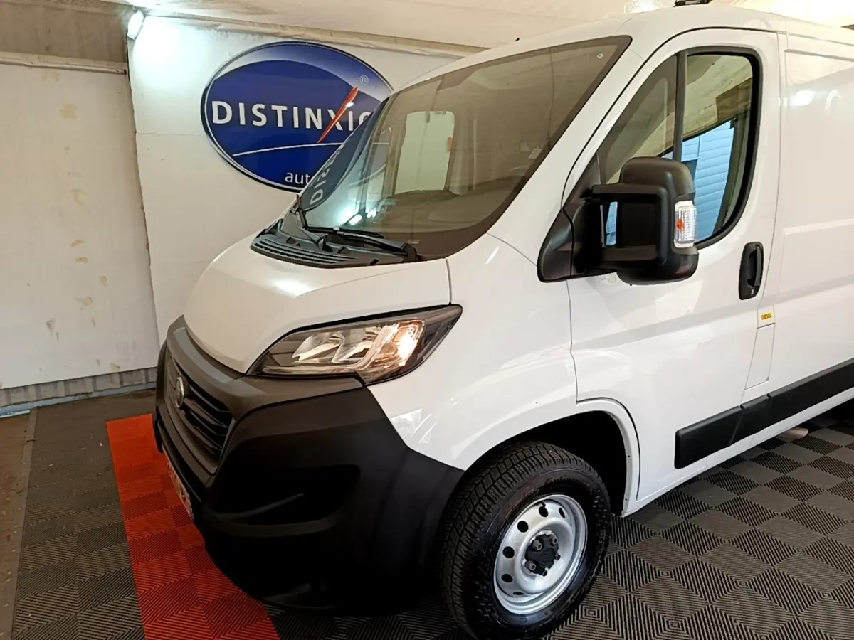 Vue 3/4 avant droit d’un fourgon FIAT Ducato blanc avec pare-chocs noirs et rétroviseur large noir.