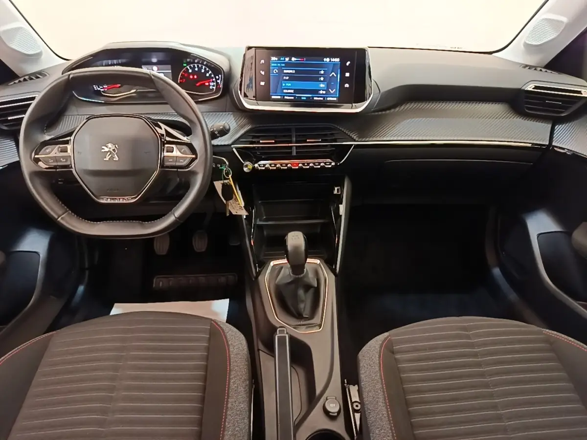 Vue intérieure avant de la Peugeot 208 PureTech 75 S&S Active Pack 2023, volant cuir multifonctions et écran tactile central.