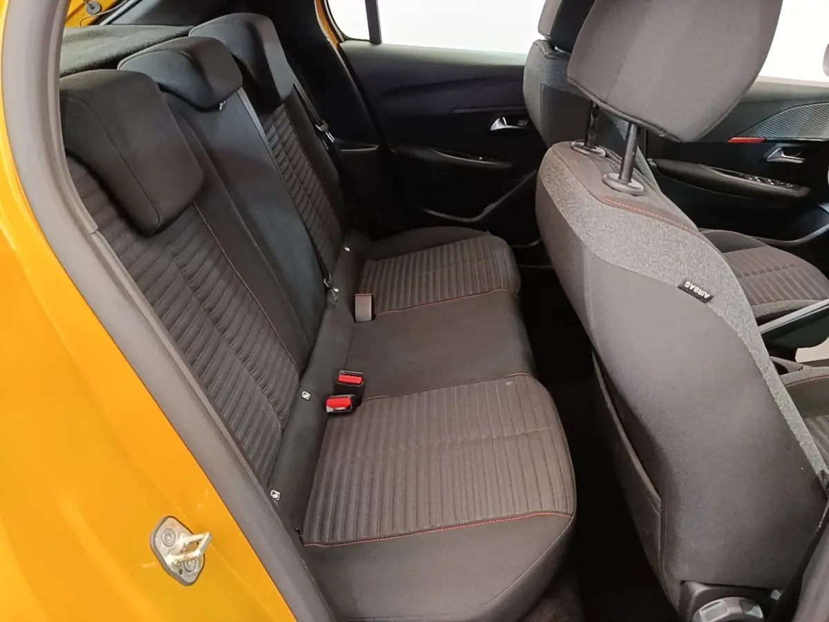 Vue intérieure arrière côté gauche de la Peugeot 208 jaune 2023, banquette tissu noir avec surpiqûres rouges.