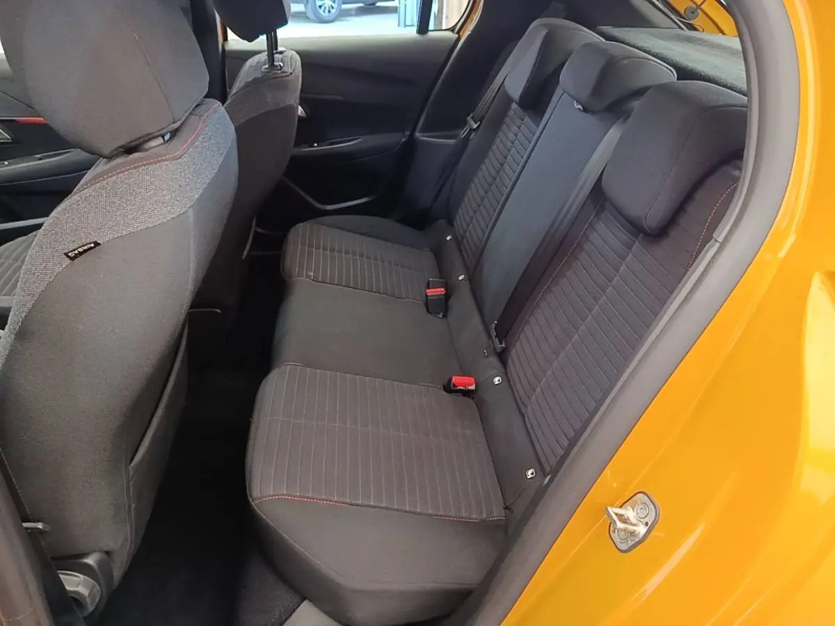 Vue intérieure côté droit sur la banquette arrière noire avec surpiqûres rouges d'une Peugeot 208 jaune 2023.
