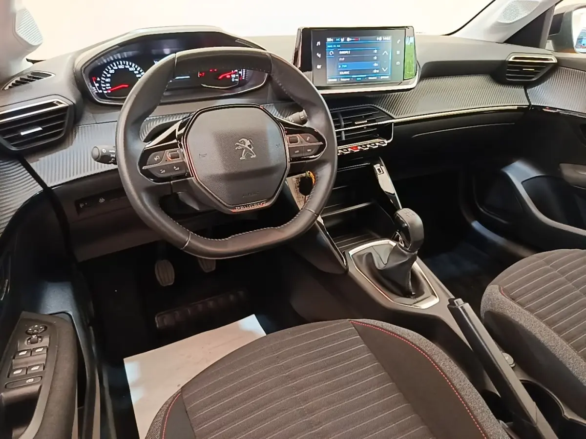 Intérieur de la Peugeot 208 PureTech 75 S&S Active Pack 2023, vue avant centrée sur le volant cuir et la console tactile.