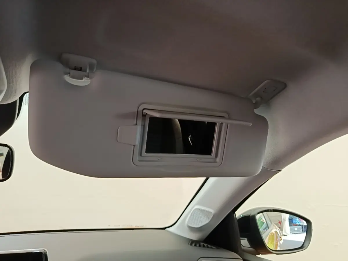Détail de pare-soleil avec miroir intégré côté conducteur dans l'habitacle d'une Peugeot 208 jaune 2023.