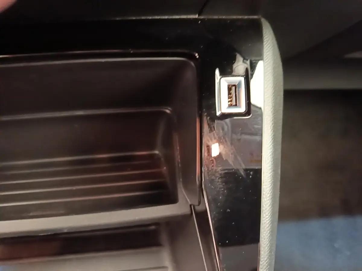 Gros plan sur la prise USB dans le rangement central intérieur de la Peugeot 208 jaune PureTech 75 S&S Active Pack 2023.