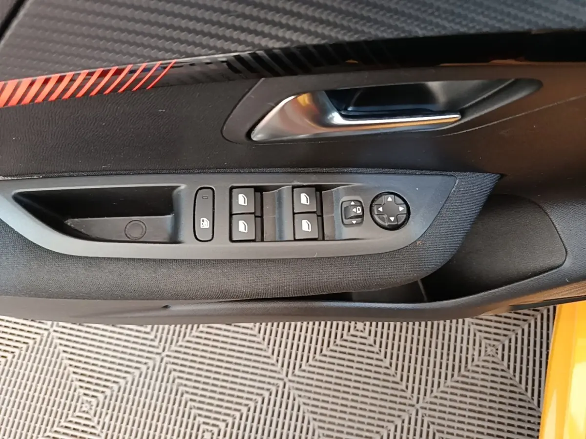 Vue rapprochée de la porte côté conducteur de la Peugeot 208 jaune, montrant les commandes des vitres et rétroviseurs.
