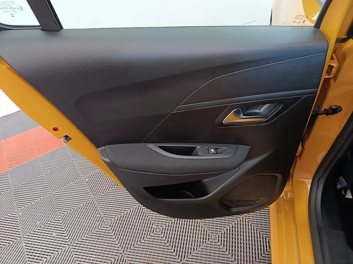 Vue intérieure de la porte avant gauche jaune de la Peugeot 208 2023 avec panneau noir et commande de vitre électrique.