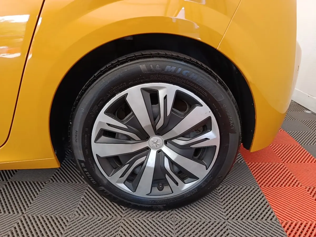 Gros plan sur la roue arrière droite d'une Peugeot 208 jaune 2023 avec jante alliage et pneu Michelin.