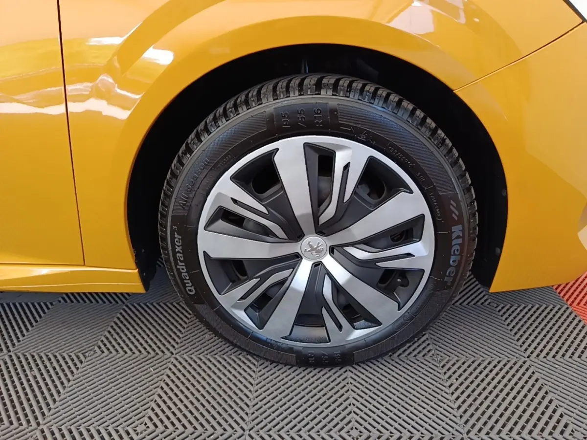 Gros plan sur la roue avant droite de la Peugeot 208 jaune 2023 avec jante alliage au design moderne.