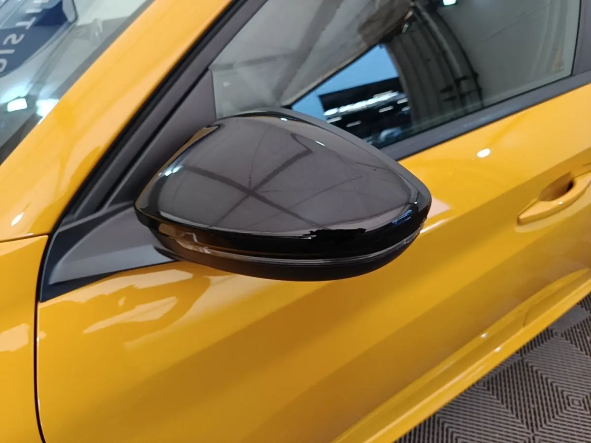 Gros plan sur le rétroviseur noir brillant côté gauche d’une Peugeot 208 jaune vif, vue latérale avant.