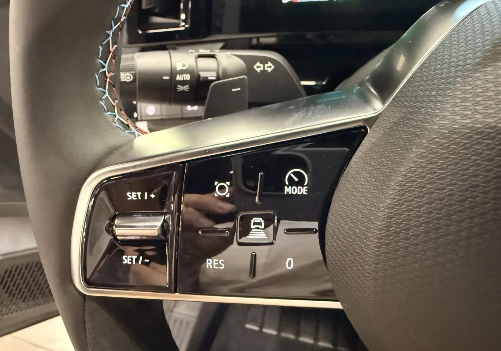 Gros plan sur les commandes du volant du Renault Austral gris Schiste, avec surpiqûres tricolores visibles.
