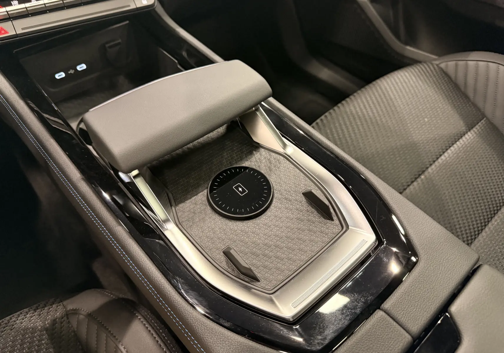 Gros plan sur la console centrale du Renault Austral gris, avec repose-bras et zone de charge sans fil visible.