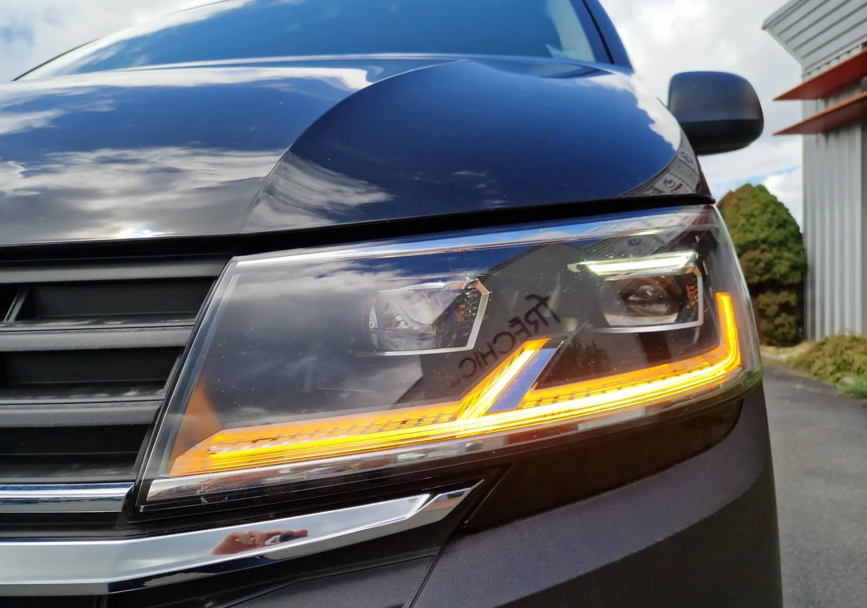 Gros plan sur le projecteur LED avant droit du Volkswagen Transporter noir avec clignotant allumé.