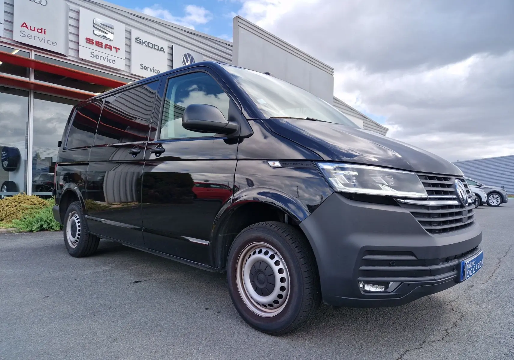 Vue 3/4 avant droit d'un Volkswagen Transporter noir 2020 finition Business Line avec projecteurs LED et caméra de recul.