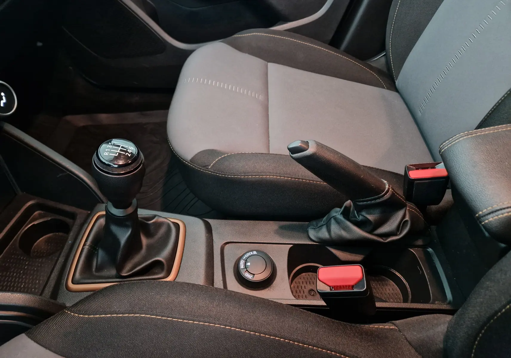 Vue rapprochée de la console centrale du Dacia Duster 2024 blanc, montrant levier de vitesse manuel et frein à main.