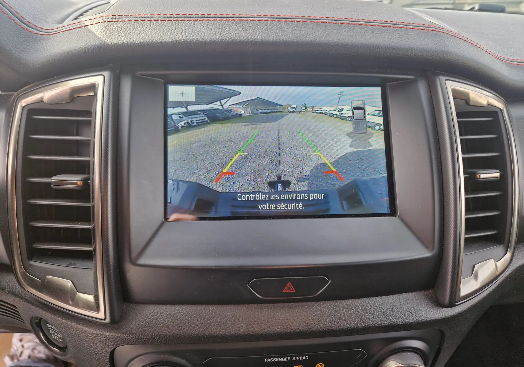 Vue intérieure du tableau de bord du Ford Ranger Raptor 2022 avec écran de caméra de recul affichant l'arrière en bleu Ford Performance.