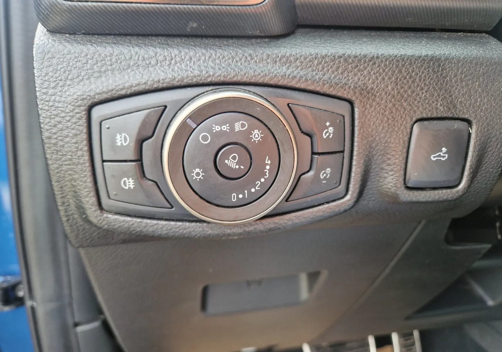 Gros plan sur le bouton de commande des phares et éclairages du Ford Ranger Raptor bleu, côté gauche du tableau de bord.