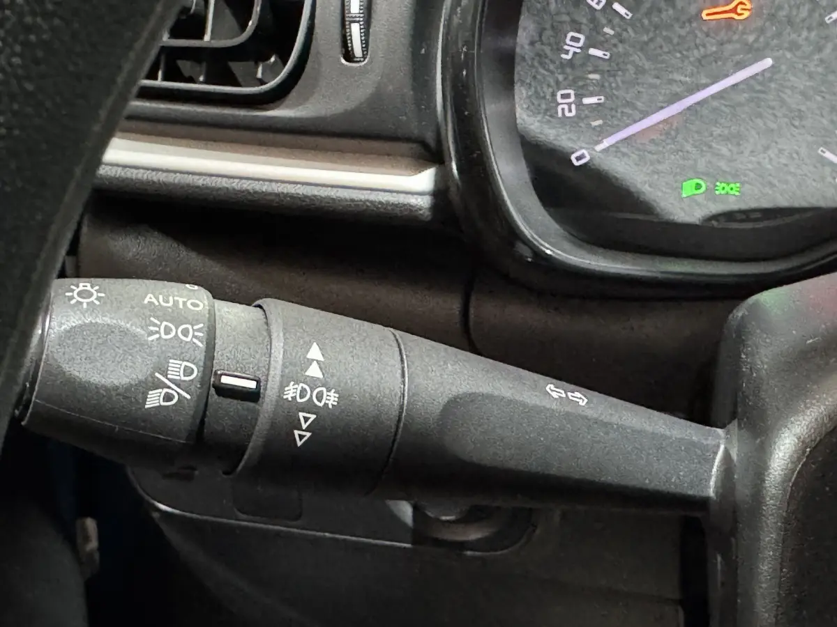 Gros plan sur la commande des phares et clignotants du volant d'une Citroën C3 2018, intérieur noir.