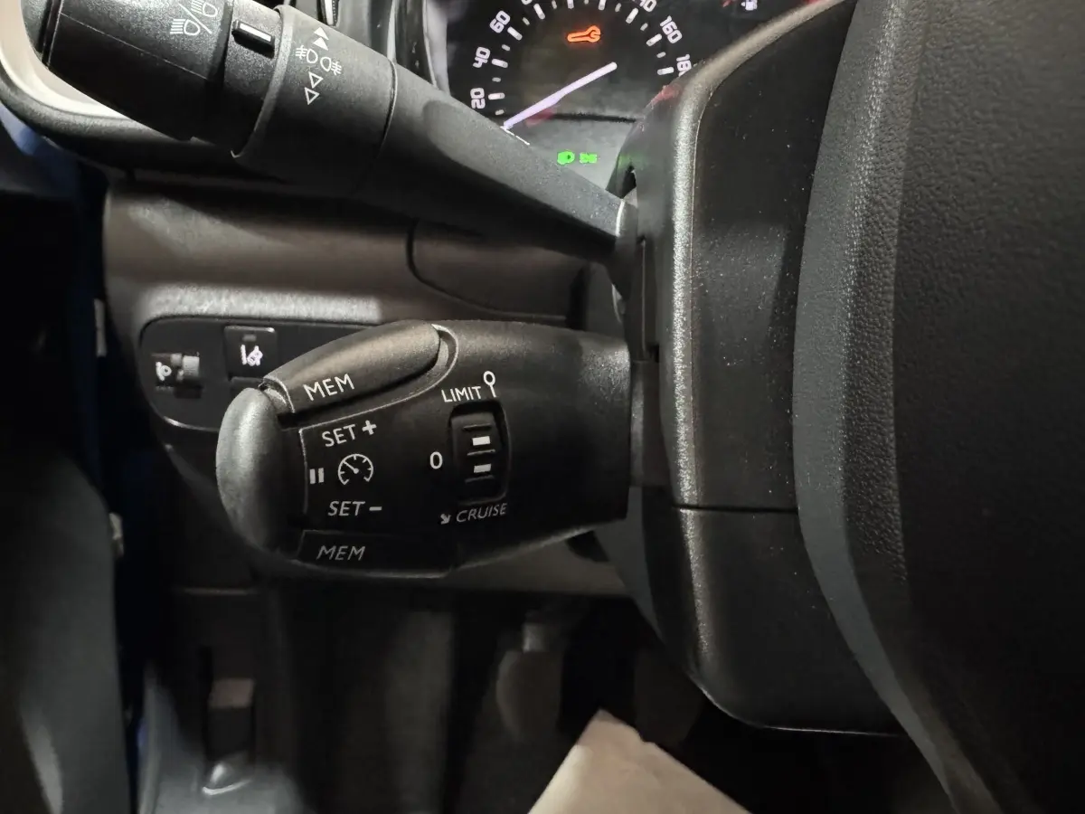 Gros plan sur la commande de régulateur de vitesse à gauche du volant d'une Citroën C3 bleu 2018.