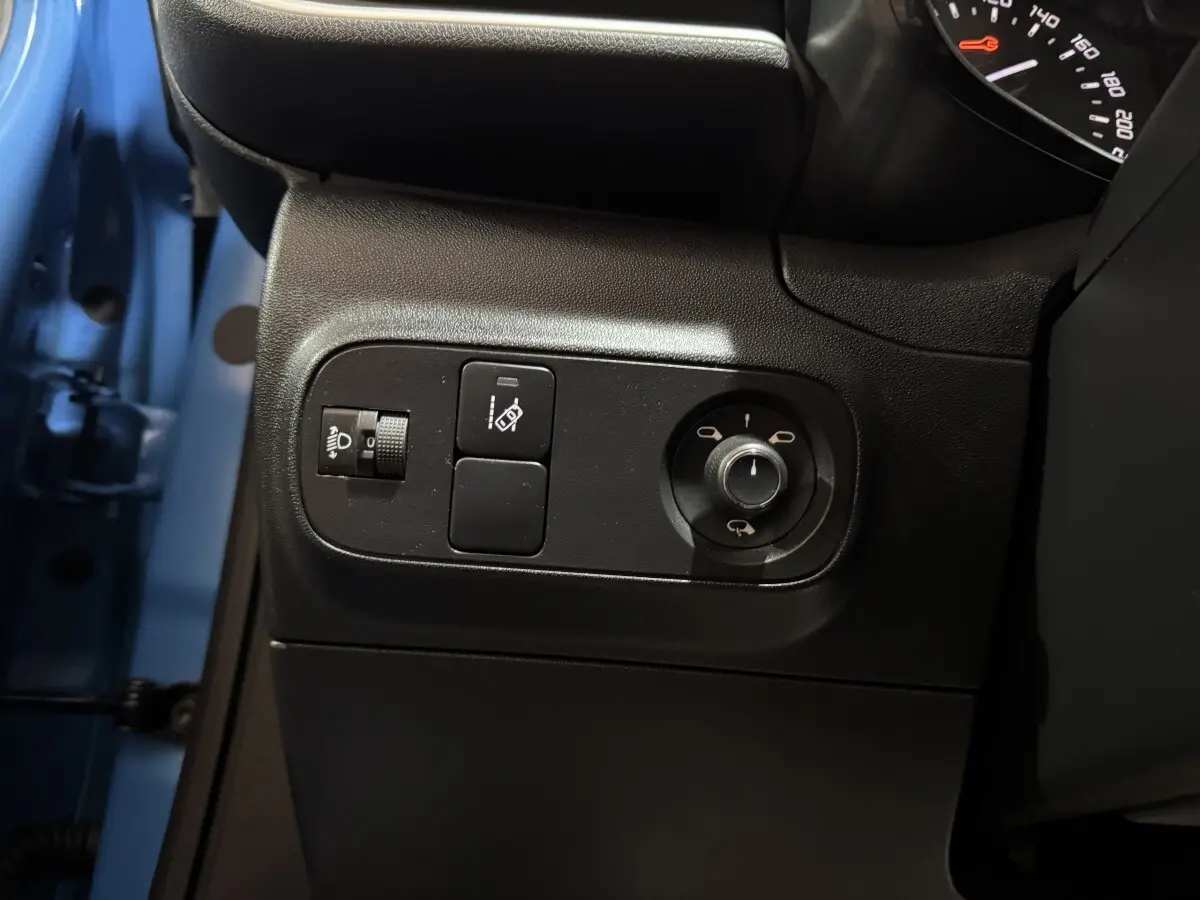 Gros plan sur les commandes côté gauche d'une Citroën C3 bleu 2018, avec réglage phares et rétroviseurs.