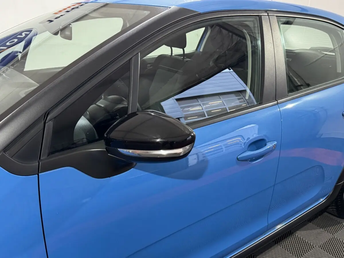 Vue latérale côté gauche d'une Citroën C3 bleu avec rétroviseur noir brillant et poignées de porte ton caisse.