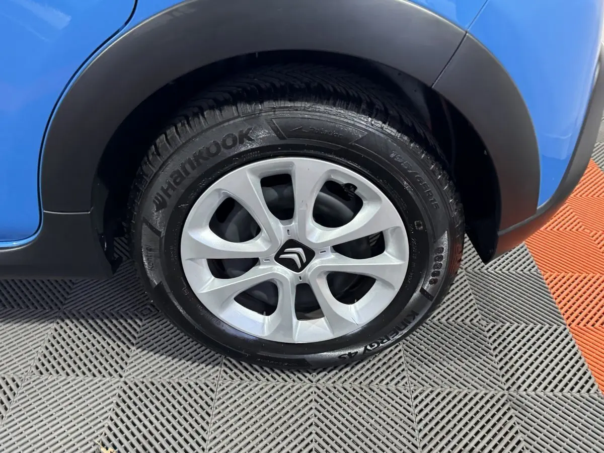 Gros plan sur la roue avant droite d'une Citroën C3 bleu 2018 avec jante argentée et logo Citroën central.