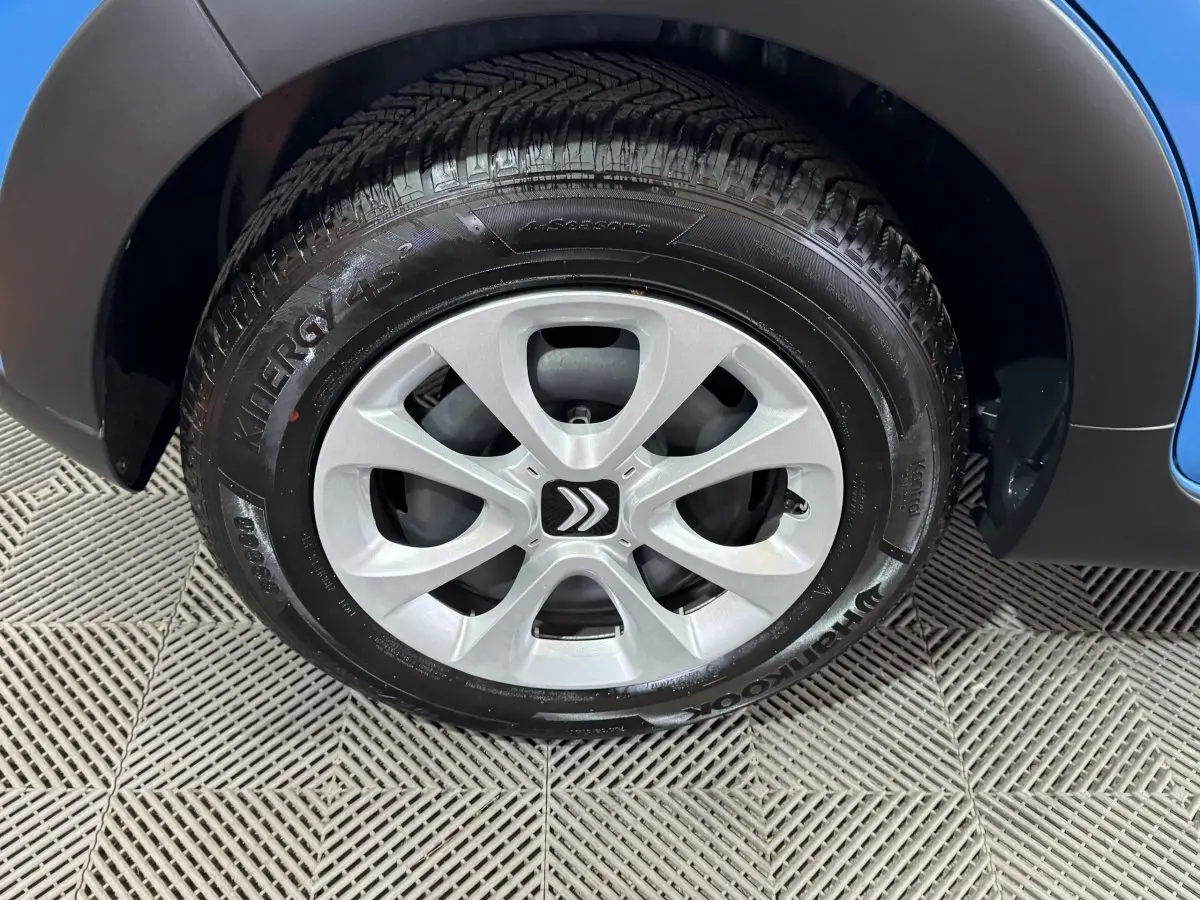 Gros plan sur la roue avant droite d'une Citroën C3 bleu 2018 avec jante argentée et logo Citroën central.