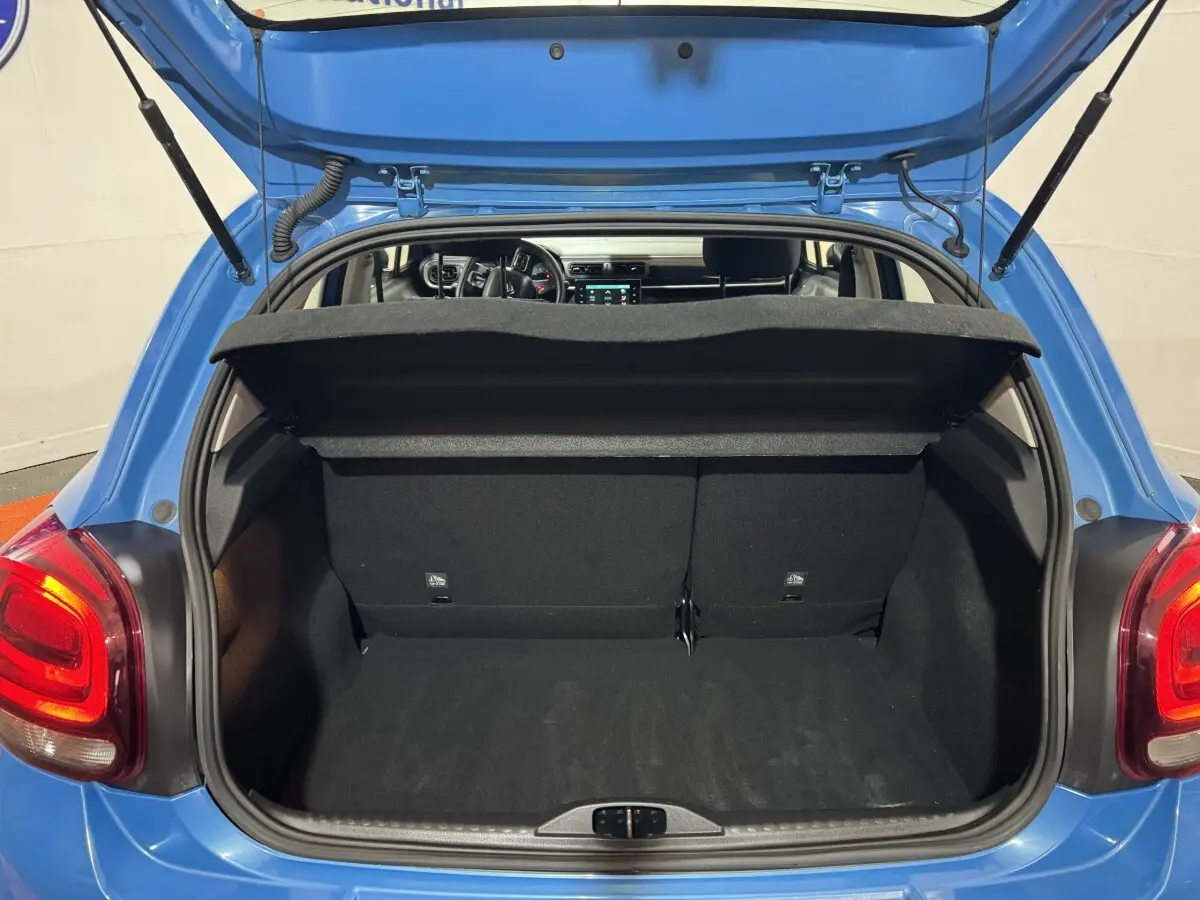 Coffre ouvert d'une Citroën C3 bleu 2018, vue arrière montrant l'intérieur spacieux et la tablette de séparation.