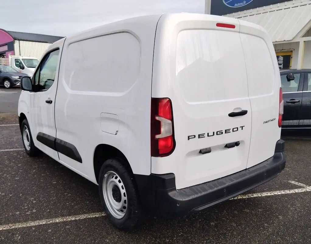 Vue 3/4 arrière droite d’un Peugeot Partner Fourgon blanc Icy avec portes arrière pleines et protections noires sur les flancs.