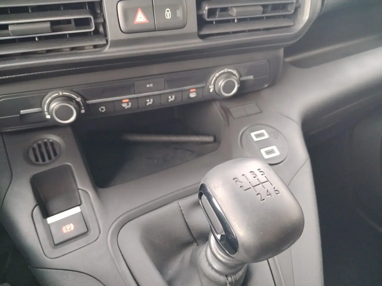 Gros plan sur le levier de vitesses manuel noir et la console centrale grise du Peugeot Partner Fourgon blanc Icy 2025.
