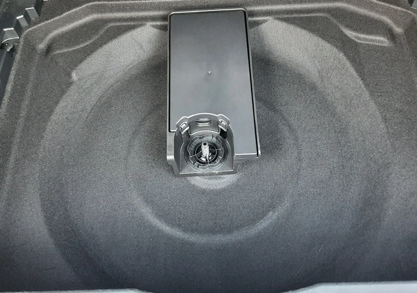 Vue plongeante sur le coffre noir du Citroën C5 Aircross Ph.2, espace de rangement vide avec fixation centrale visible.