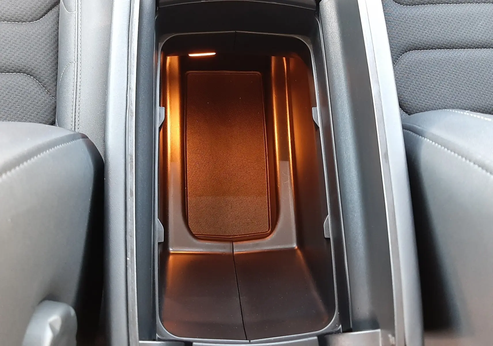Vue plongeante sur le rangement central intérieur éclairé du Citroën C5 Aircross 2024, finition tissu gris et cuir noir.