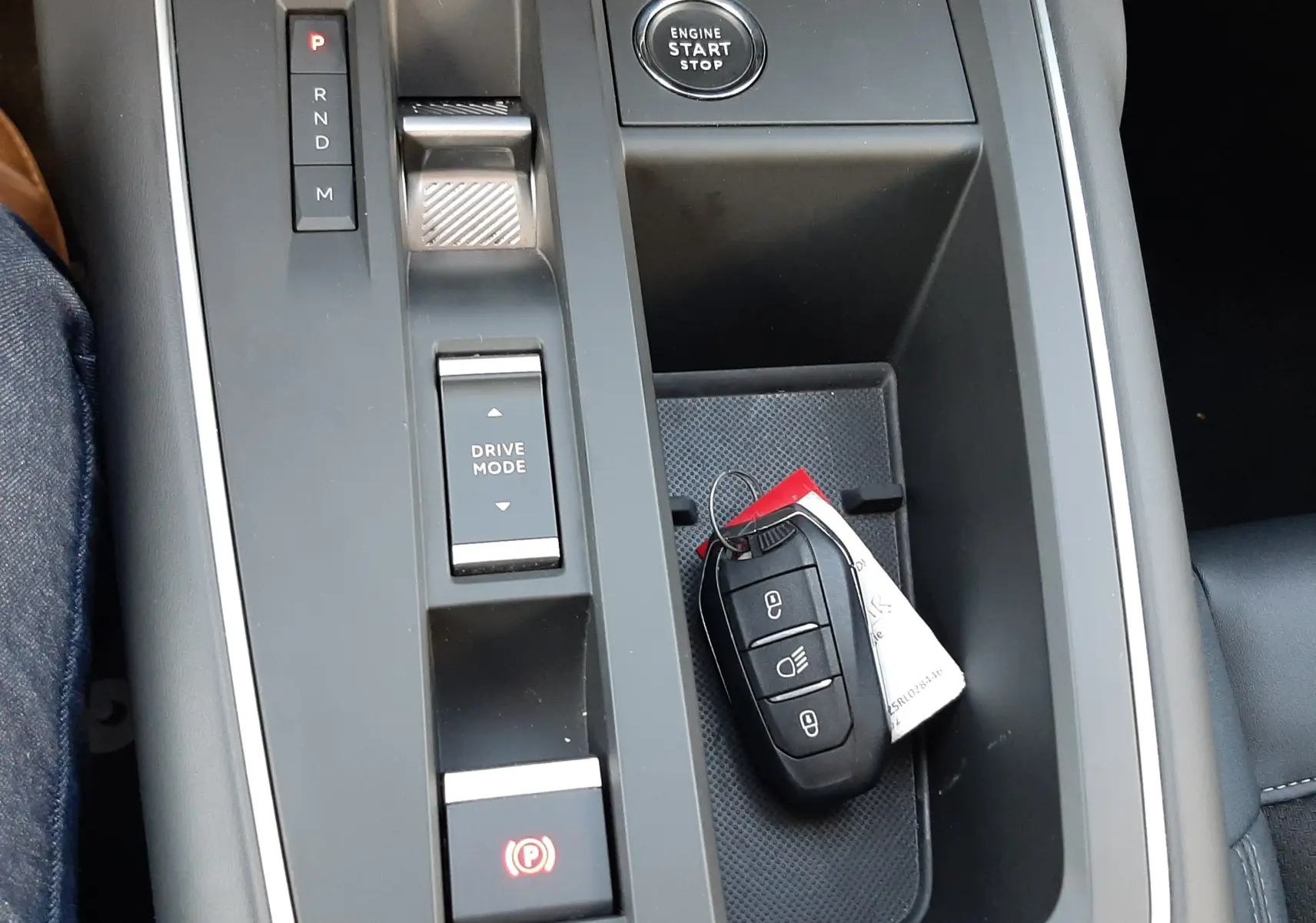 Vue rapprochée de la console centrale noire du Citroën C5 Aircross 2024, avec bouton start/stop et clé posée.
