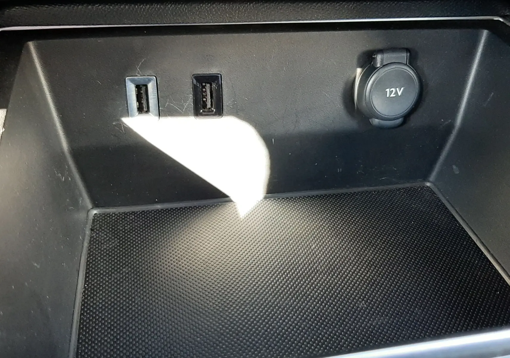 Gros plan sur la console centrale noire du Citroën C5 Aircross 2024, montrant deux ports USB et une prise 12V.