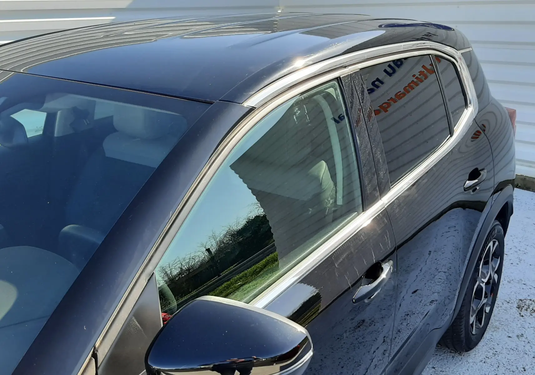 Vue côté gauche en 3/4 avant d'un Citroën C5 Aircross noir Perla Nera avec rétroviseur et jantes visibles.