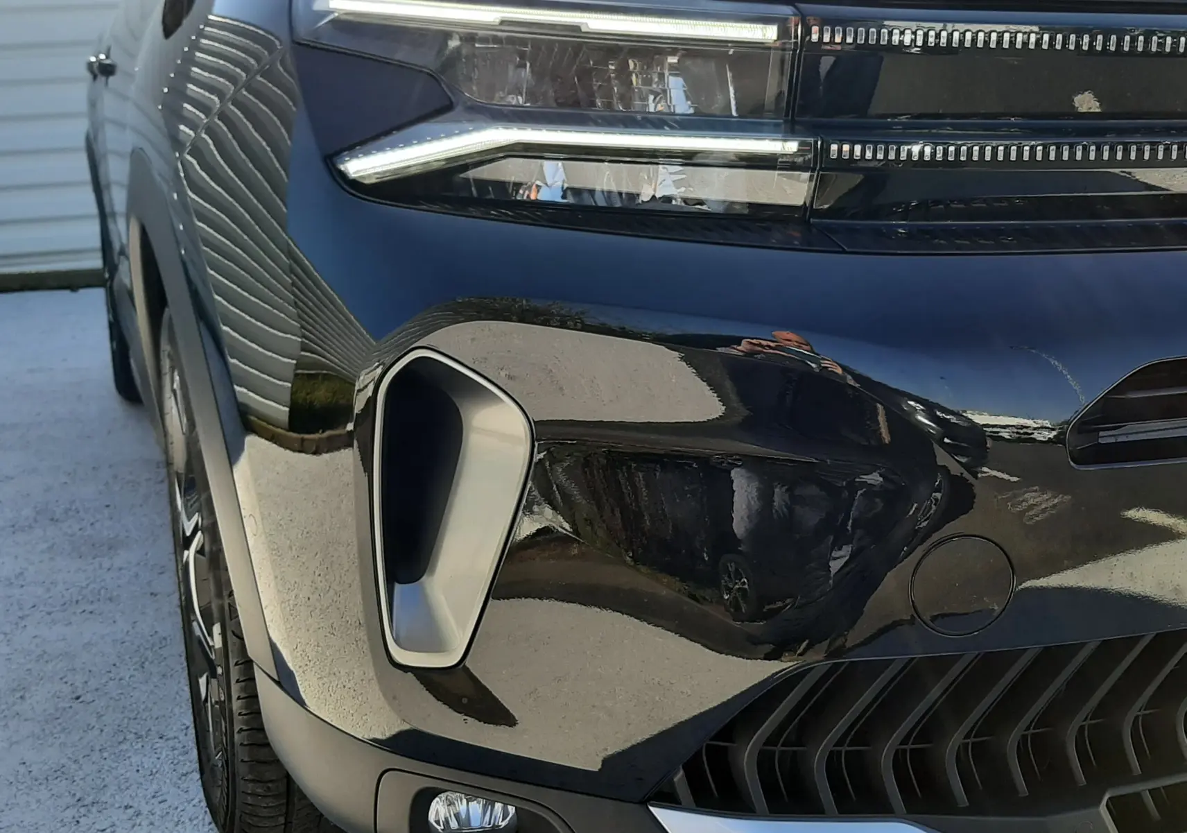 Gros plan sur l'avant gauche du Citroën C5 Aircross noir Perla Nera, mettant en valeur les phares LED et la calandre moderne.
