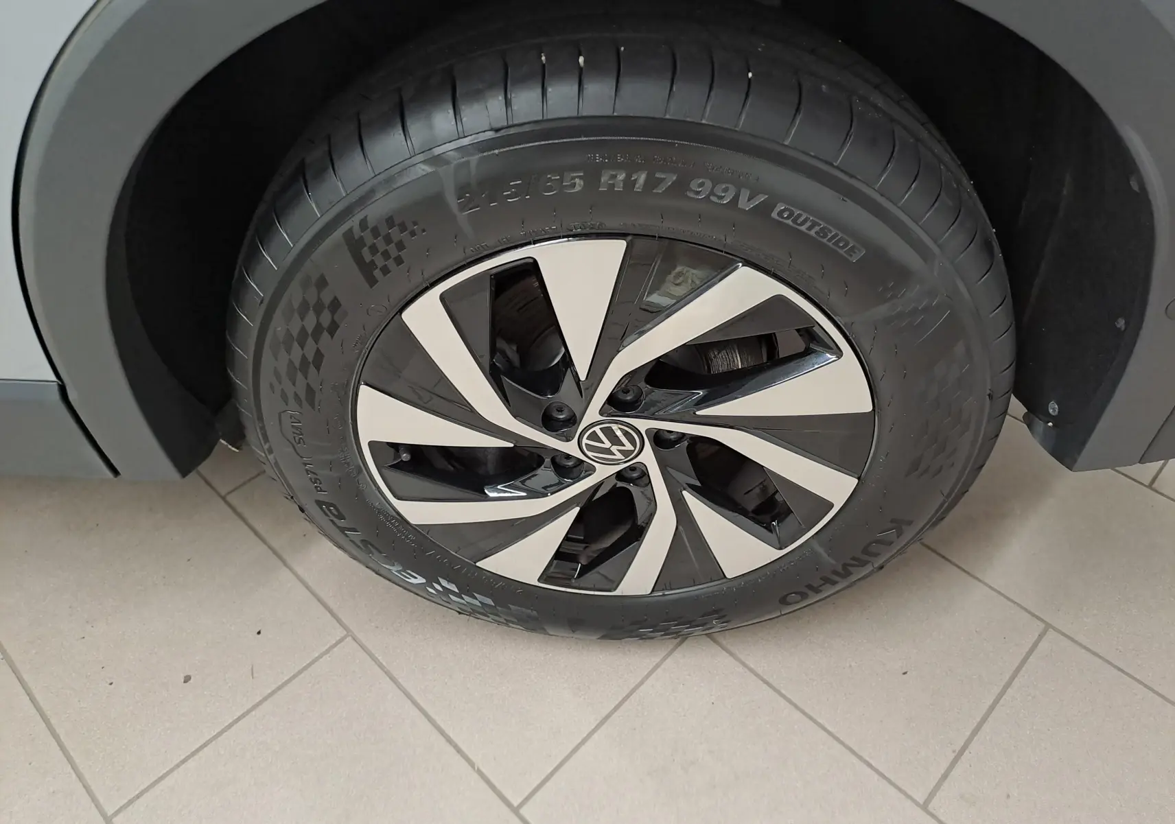 Gros plan sur la roue avant droite du Volkswagen Tiguan 2.0 TDI 150 DSG7 VW Edition avec jante alu bicolore et carrosserie argent Dolomite.