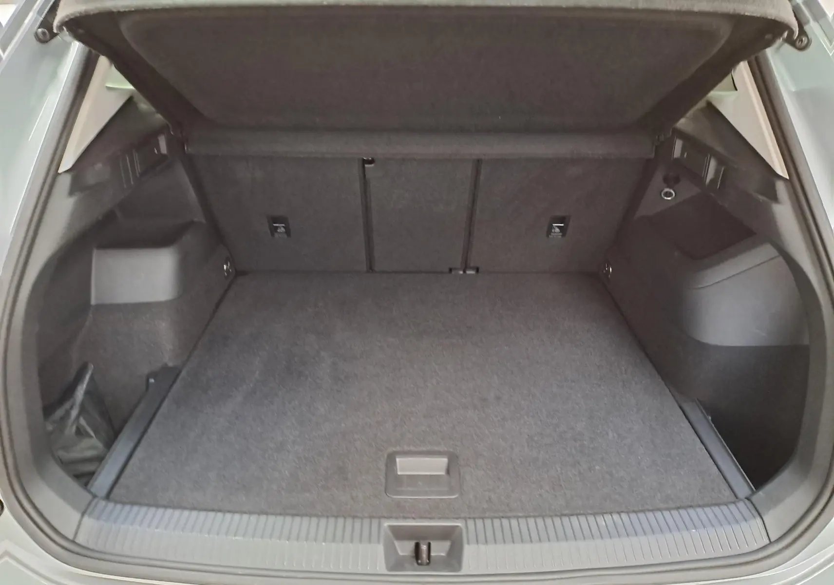 Vue intérieure du coffre ouvert du Volkswagen Tiguan 2.0 TDI 150 DSG7 VW Edition, avec revêtement gris foncé.