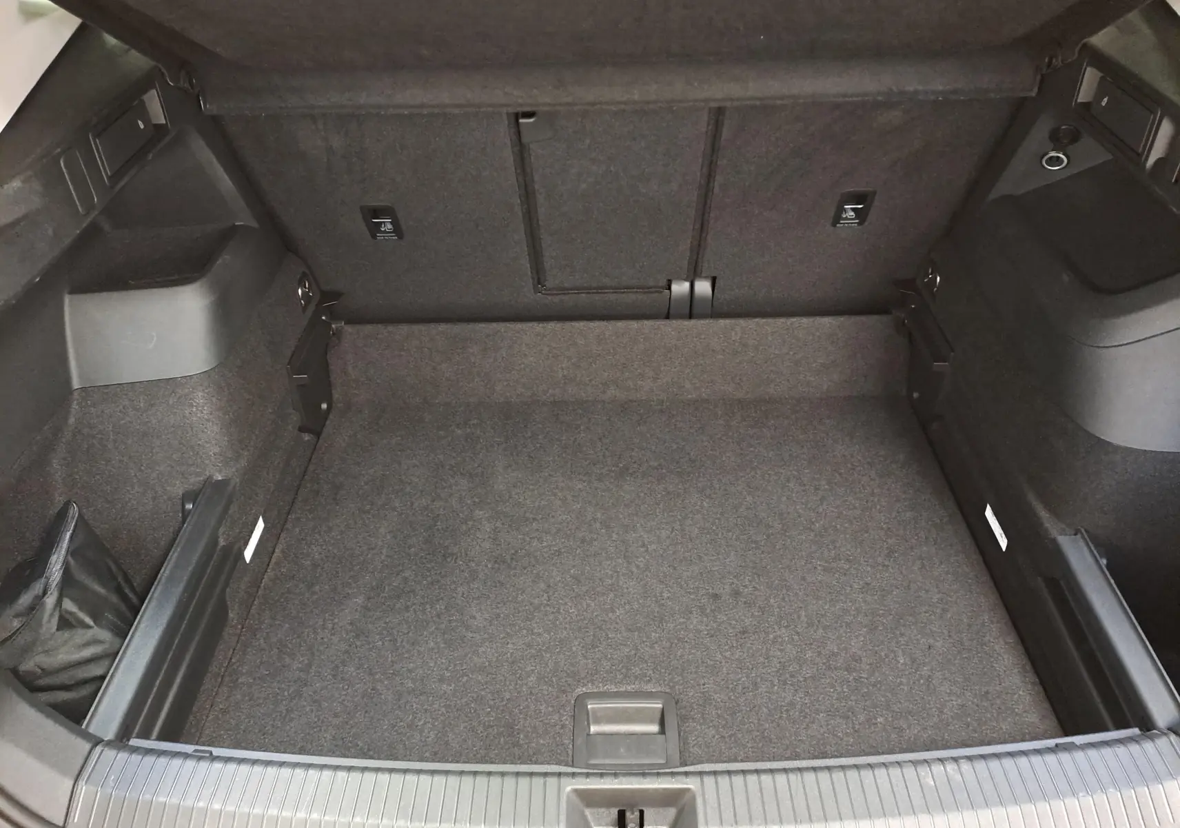Vue intérieure du coffre spacieux et propre du Volkswagen Tiguan 2025, avec revêtement gris foncé uniforme.